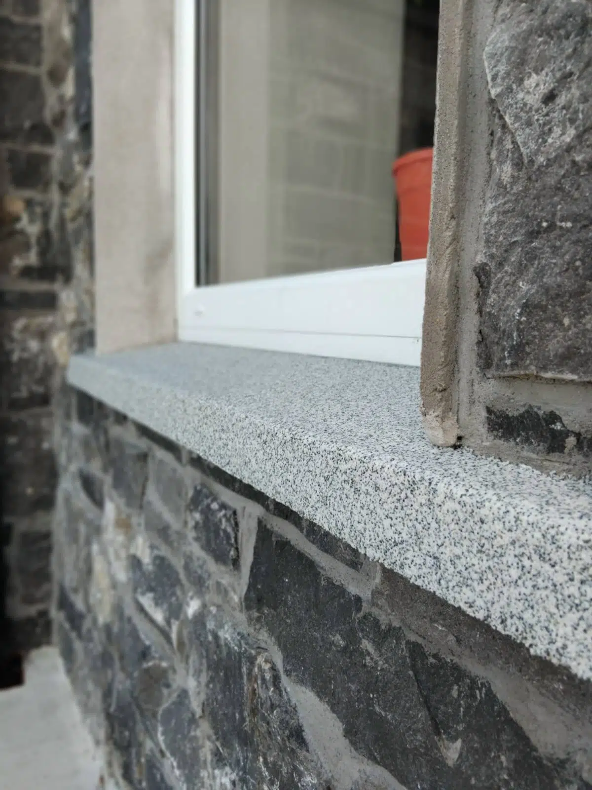 Completed speckled Decosill window sill against a stone facade